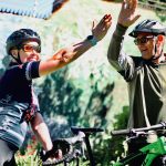 Alison Blair and Craig Vandeleur giving each other a high five with their bicycles